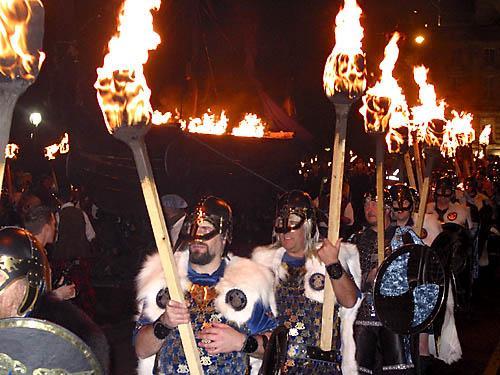 Wigged vikings carry flaming torches